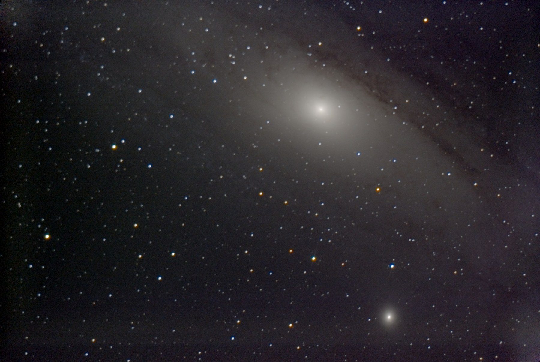 The bright core of the Andromeda Galaxy with dark dust lanes, and a small companion galaxy below