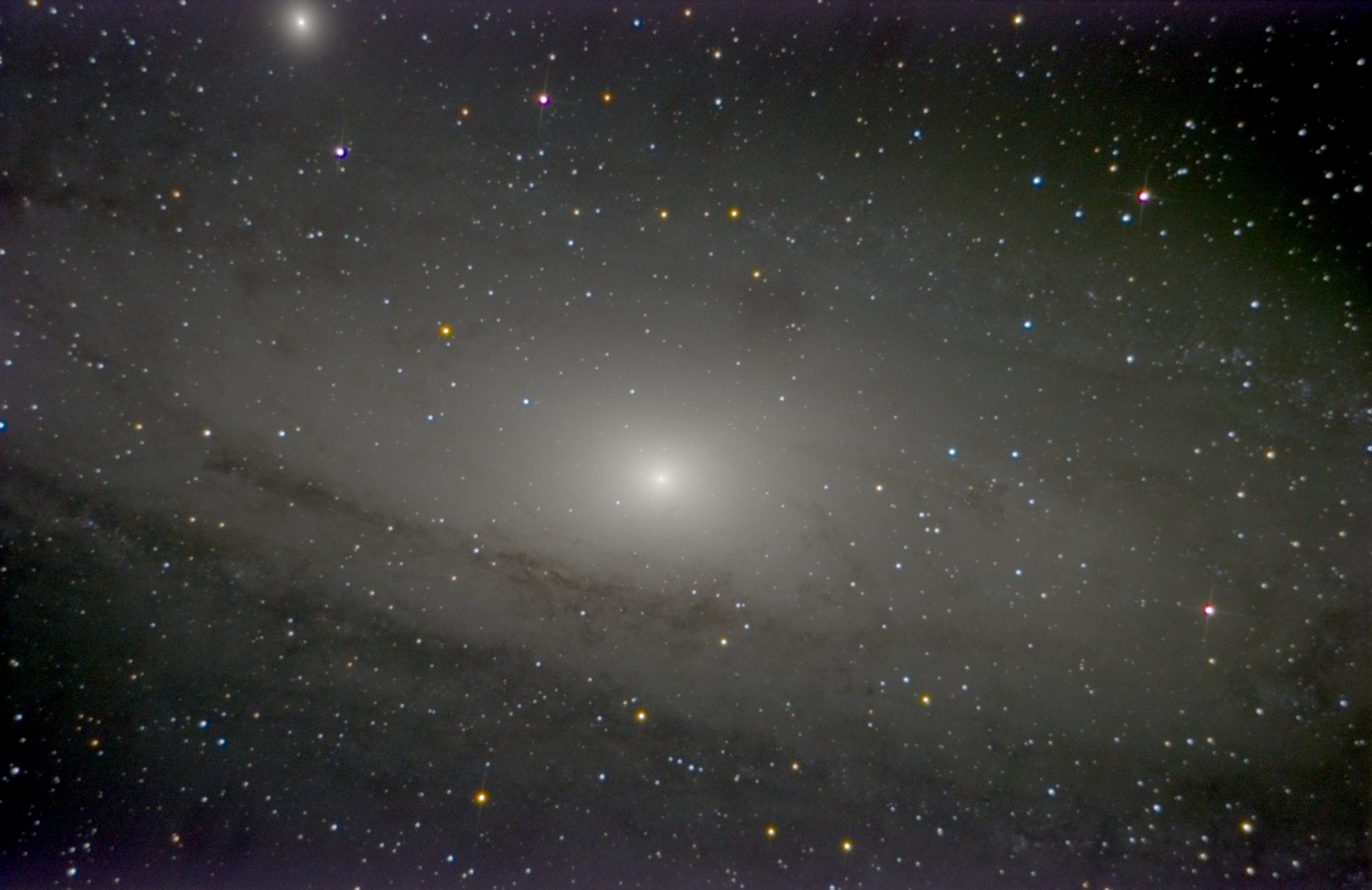 The Andromeda Galaxy's bright core with dark dust lanes sweeping across below it, and the companion M32 at top left