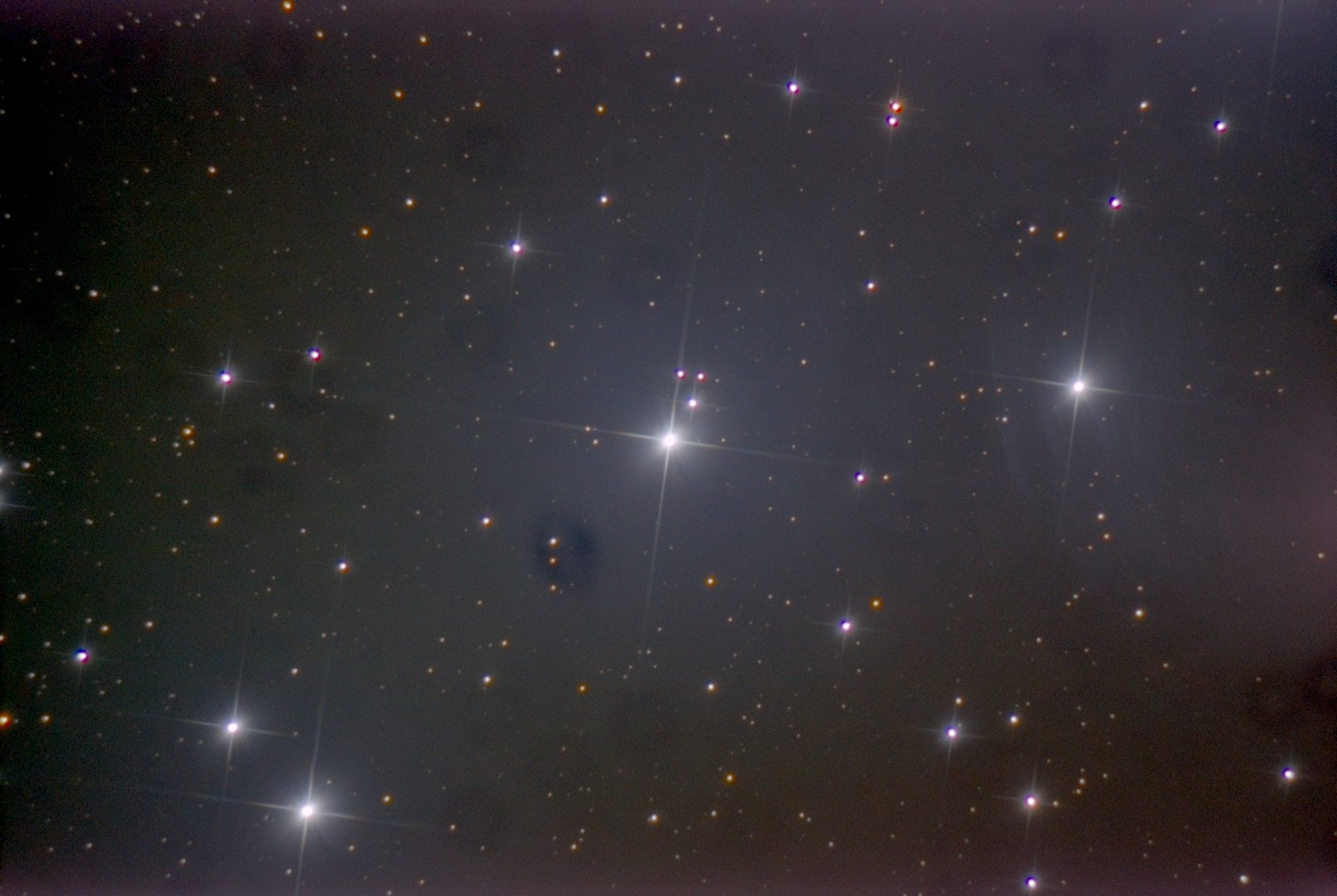 The bright stars of the Pleiades with long diffraction spikes and a faint blue haze around them